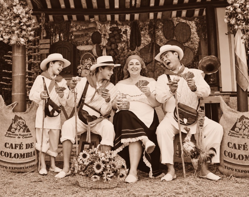 Fotografía en sepia: la familia vestida de arrieros, con naipes en la mano y expresión de sorpresa, como si alguien hubiera hecho trampa