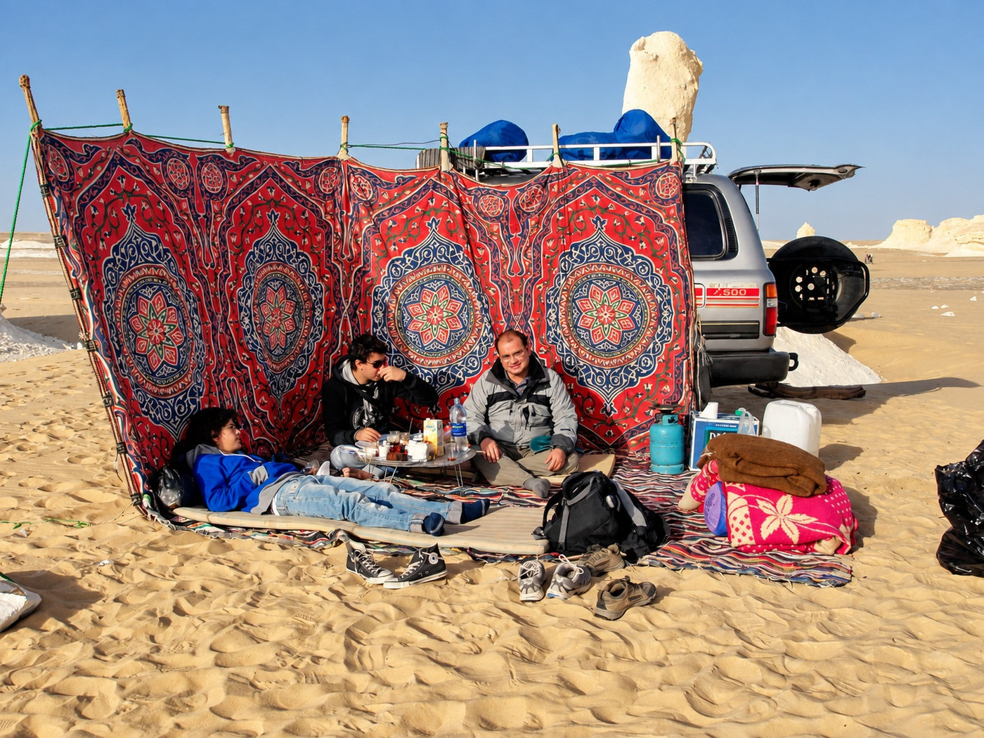 Campamento en el Desierto Blanco: un biombo de tela, una mesa baja en la arena y el todoterreno al fondo