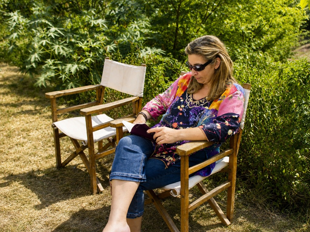 Alexandra leyendo en el jardín, sentada en una silla de director
